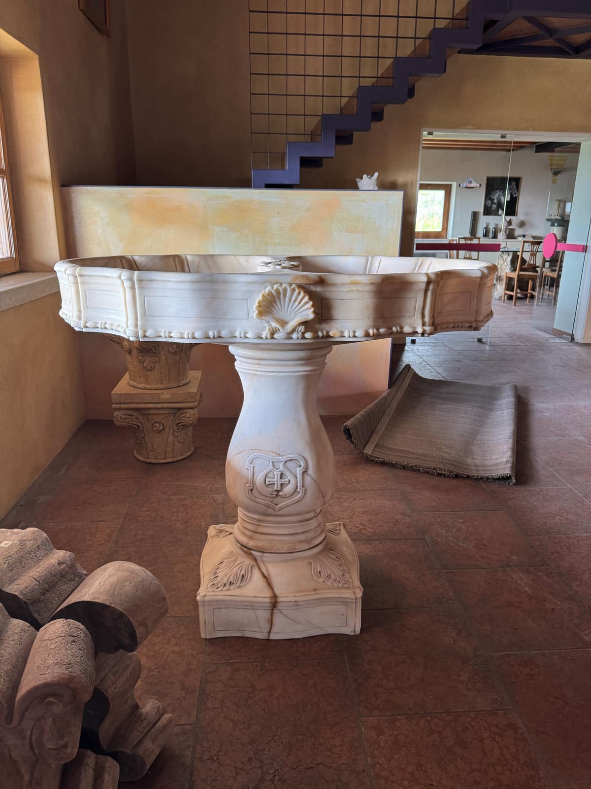 Fontana in marmo bianco con motivi a conchiglia nella sala grande, frammenti di colonne in primo piano