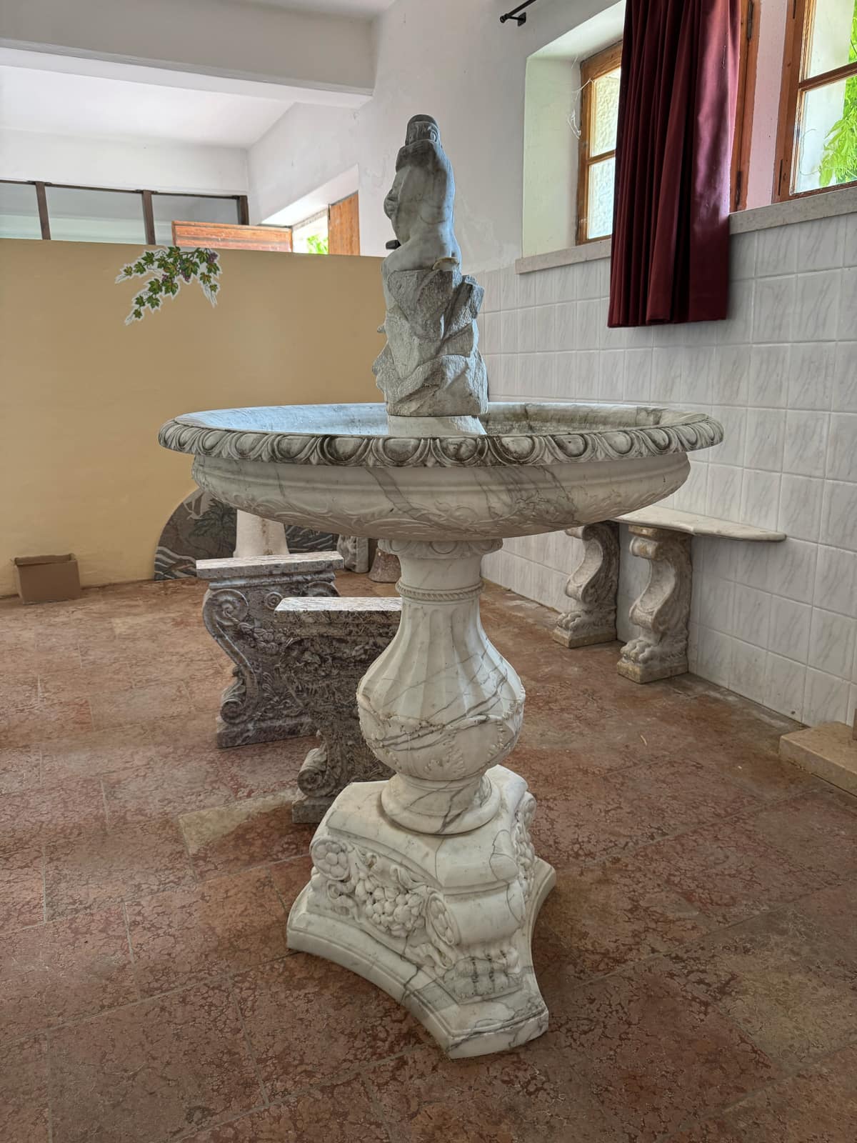 Fontana a più vasche in marmo grigio venato sormontata da una figura, sotto il lucernario